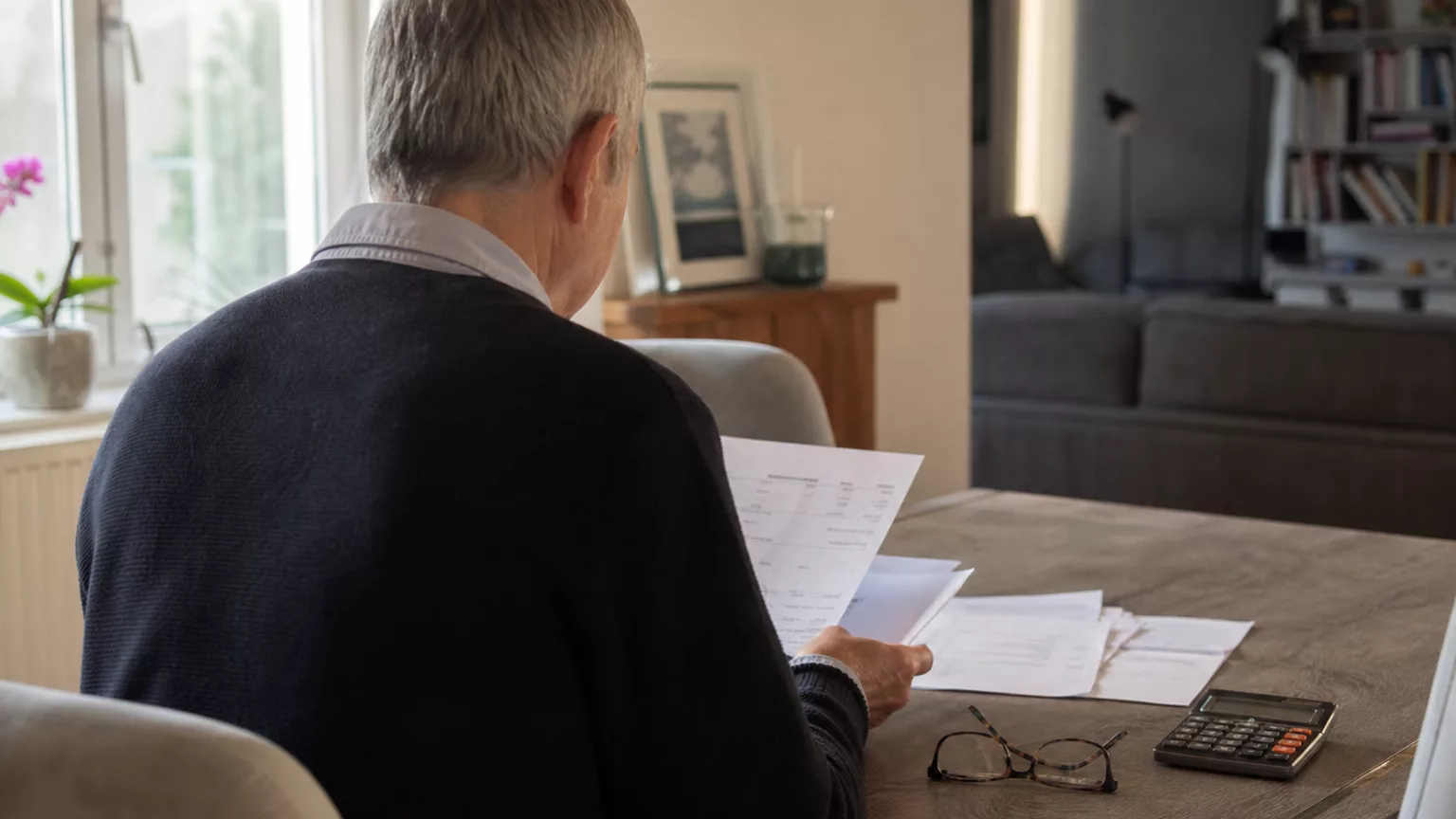 Une personne retraitée examine son budget à la table de son logement.