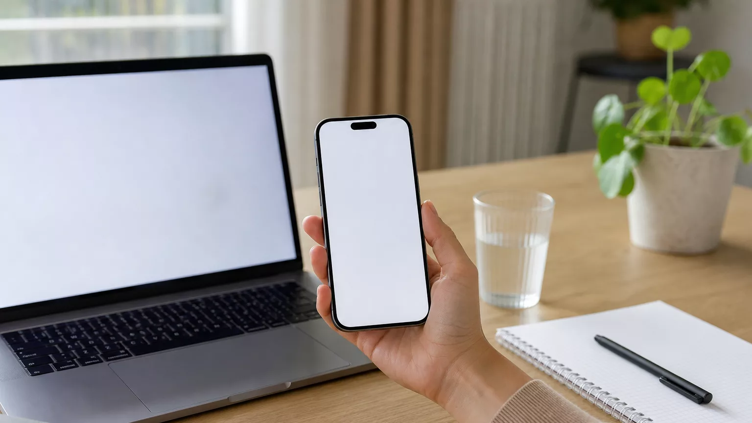 Un téléphone portable tenu près d’un ordinateur sur un bureau.