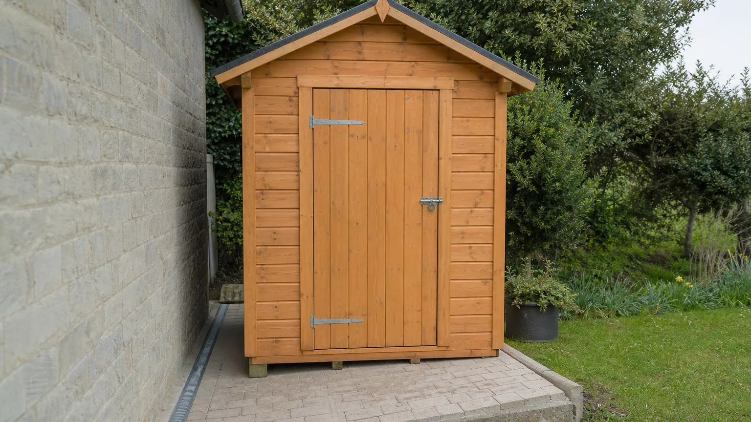 Abri de jardin indépendant installé à côté d’un mur, avec un espace entre les deux.
